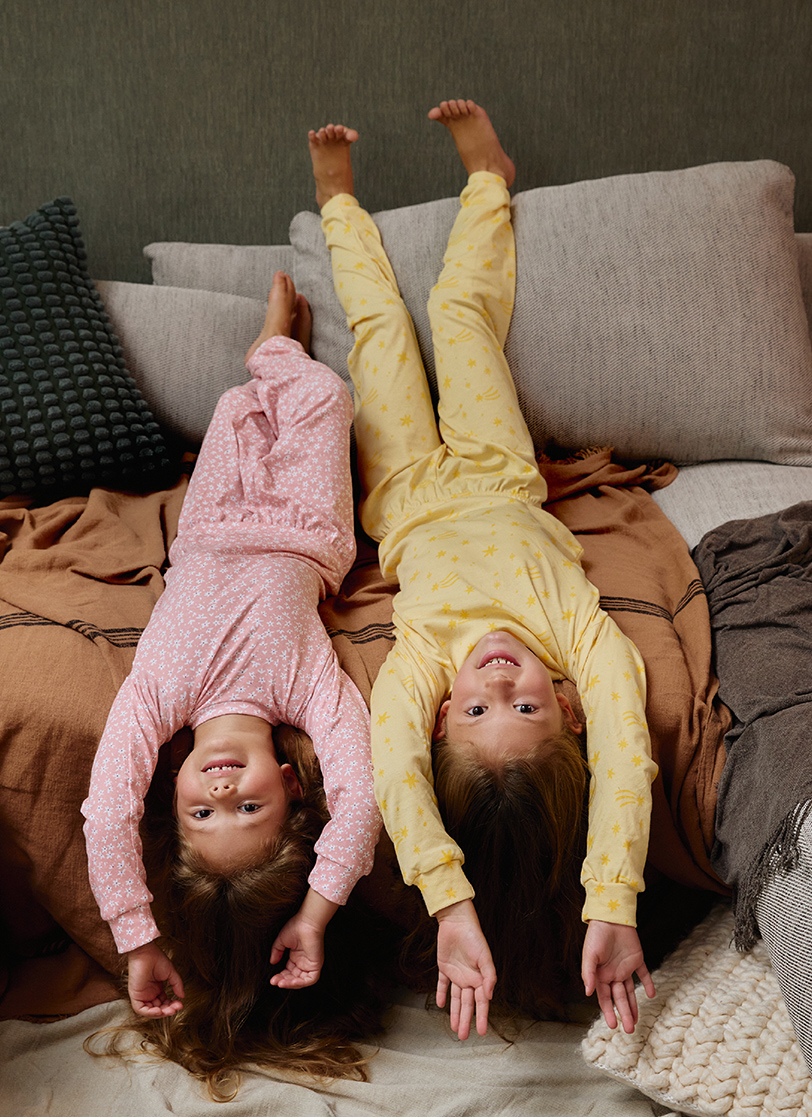 Djevojčice leže na krevetu u žutoj i roze pidžami na dug rukav