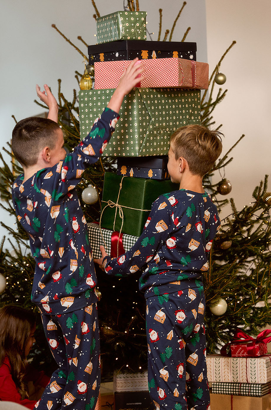 Dječaci stoje pored jelke i poklona u novogodišnjim pidžamama