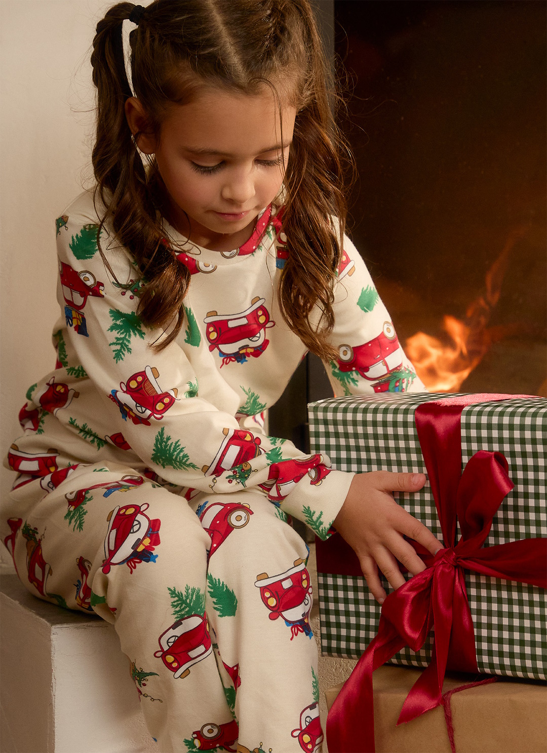 Djevojčica u novogodišnjoj pidžami otvara poklon