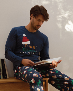 Muškarac  u novogodišnjoj pidžami drži knjigu